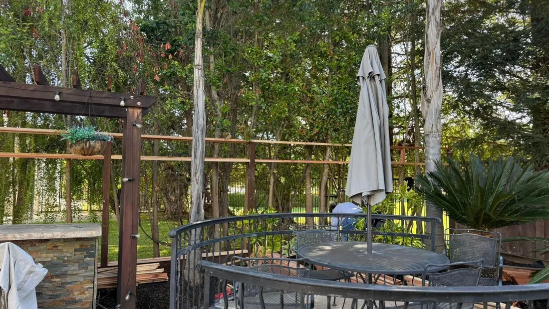 Fence line behind a covered patio and outdoor dining table