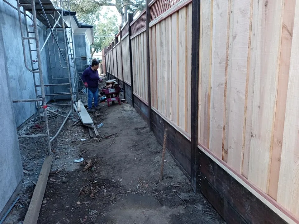 Board fence with a lattice top going up alongside a house in Salinas