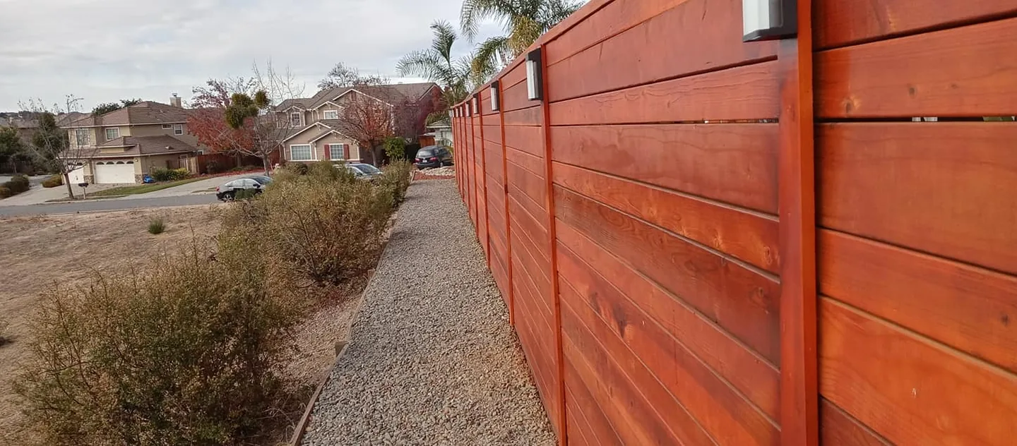 Finished redwood fence line with horizontal boards running along a front yard
